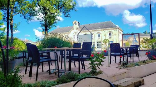 a table and chairs in front of a building at Hôtel JurJura in Dole