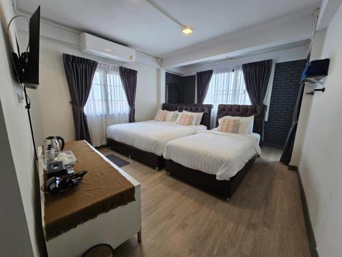 a hotel room with two beds and a television at Charma Home Watket in Chiang Mai
