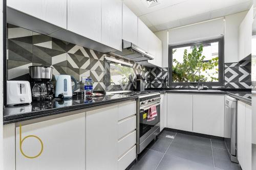 a kitchen with white cabinets and black counter tops at Bookable - 3 Bed Villa Damac Hills 2 in Dubai