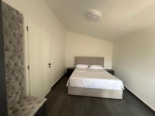 a white bedroom with a bed and a chair at Le stanze della luna in Kamëz
