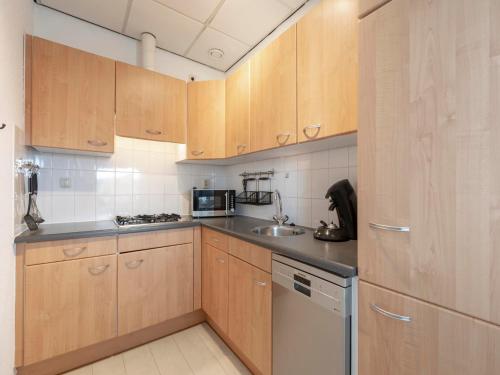 a kitchen with wooden cabinets and a sink at Beachside home with balcony in Julianadorp
