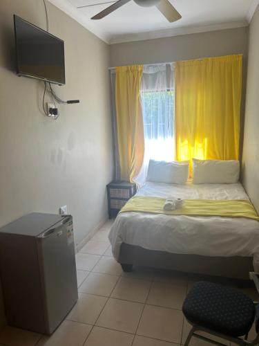 Schlafzimmer mit einem Bett und einem Fenster mit gelben Vorhängen in der Unterkunft C'est Si Bon Accommodation at 73 Geyser, Mokopane in Mokopane