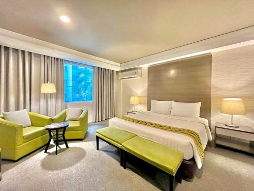 a hotel room with a large bed and yellow chairs at 88 Courtyard Hotel in Manila
