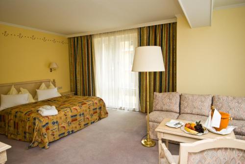 a hotel room with a bed and a couch at Thermal Resort Hotel Elisabethpark in Bad Gastein