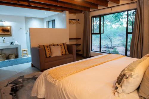 a bedroom with a large bed and a chair at Nzenga Lodge in Hoedspruit