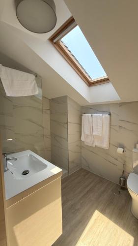 a bathroom with a sink and a toilet and a skylight at Apartamentos Boutique Don Miguel in Noja