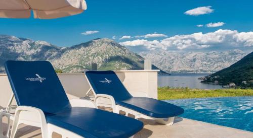 two blue chairs sitting next to a swimming pool at The Seaside Gem in Donji Morinj