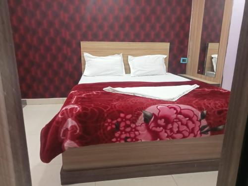 a bedroom with a bed with a red comforter at Hotel Regal Heights in Deoghar