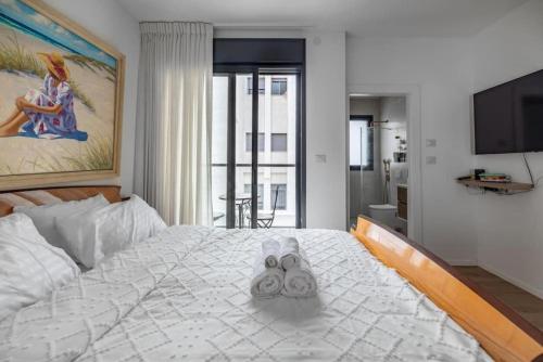 a bedroom with a large white bed with towels on it at Luxurious Central Raanana Flat with Terrace in Ra‘ananna