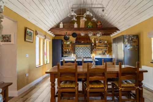 a dining room with a table and a kitchen at The Auld Shack in Cornamucklagh