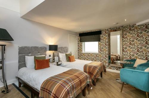 a hotel room with two beds and a blue chair at Willow Lodge Hambleton in Poulton le Fylde