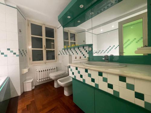 a green and white bathroom with a toilet and a sink at LA VOLPINA - Terrazza in Centro in Ovada