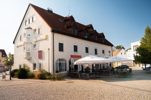 a building with tables and umbrellas in front of it at Hotel und Restaurant Rosenkranz in Markranstädt