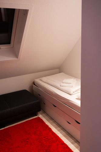 a small bedroom with a bed and a red rug at Hotel und Restaurant Rosenkranz in Markranstädt