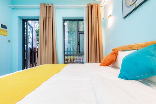 a bedroom with a large white bed with orange and blue pillows at wushe hotel in Dunhuang