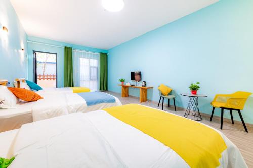 two beds in a room with blue and yellow at wushe hotel in Dunhuang