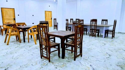 a group of wooden tables and chairs in a room at AKR Rooms in Mannar