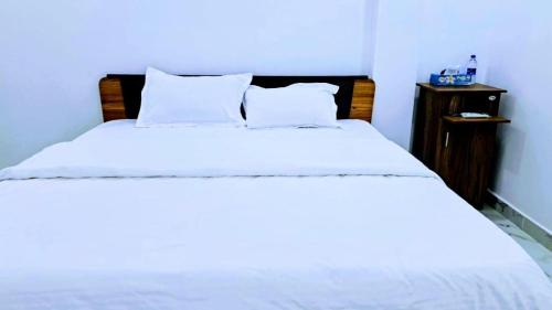 a bedroom with a large white bed with a night stand at AKR Rooms in Mannar