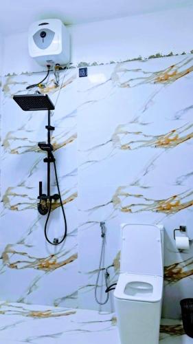 a bathroom with a toilet and a camera on a wall at AKR Rooms in Mannar