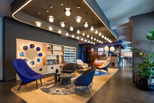 a waiting room with blue chairs and a table at ibis Styles Katowice Airport in Pyrzowice