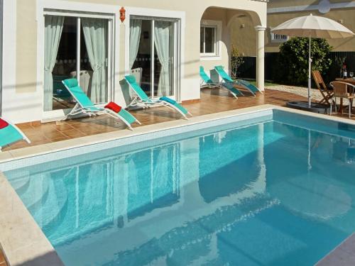 a swimming pool with chairs and an umbrella at Villa in Carvoeiro near Beach & Pool in Carvoeiro