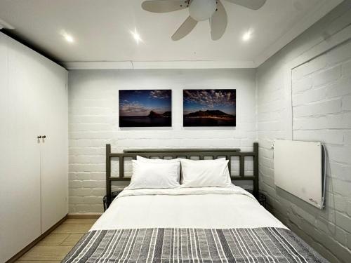 a bedroom with a bed with a ceiling fan at Harbor View Cottage in Hout Bay