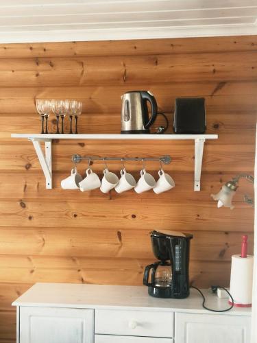 a wooden wall with a rack of coffee mugs at Hietajärven Helmi in Joensuu