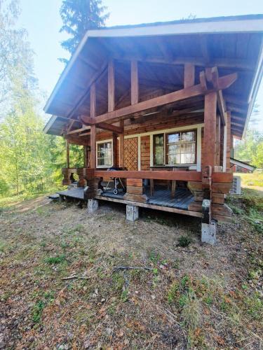 a log cabin with a large porch on a field at Hietajärven Helmi in Joensuu