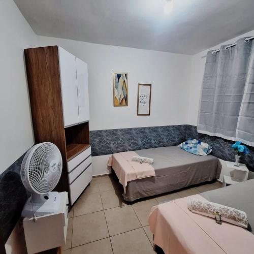 a small bedroom with two beds and a fan at Pedacinho de Lar in João Pessoa