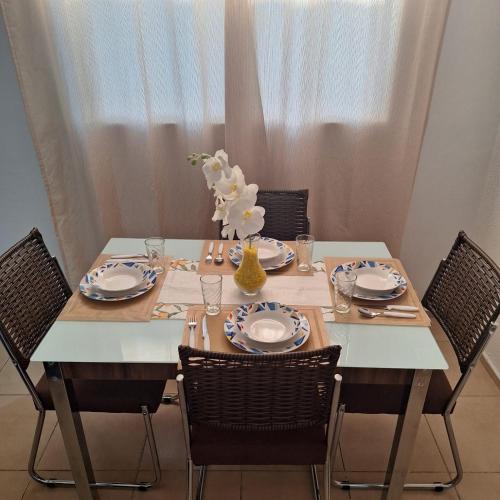a table with chairs and a white table with plates and glasses at Pedacinho de Lar in João Pessoa
