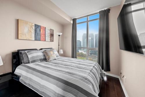 a bedroom with a bed and a large window at Downtown Condo with Picturesque View in Toronto