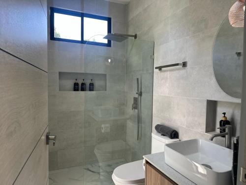 a bathroom with a shower and a toilet and a sink at Villa 7 min to Beach in Quepos