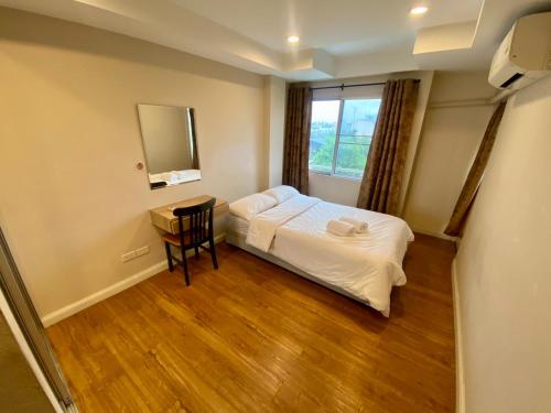 a bedroom with a bed and a table and a window at ศรีย่าน เรสซิเดนซ์ Sriyan Residence in Dusit