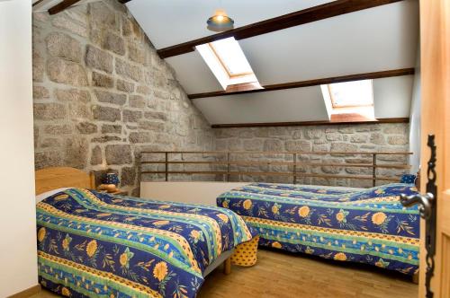 two beds in a room with a stone wall at Gites de france aux badieux in Les Badieux