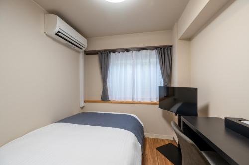 a bedroom with a bed and a flat screen tv at Sleep Inn Gotanda in Tokyo