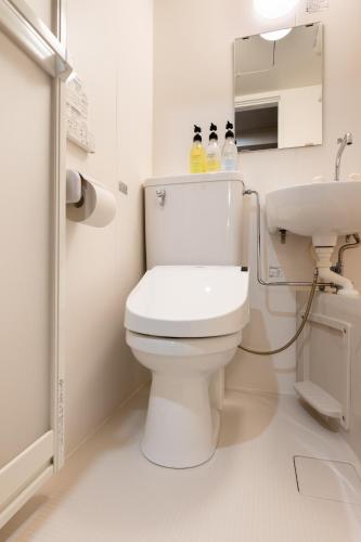 a white bathroom with a toilet and a sink at Sleep Inn Gotanda in Tokyo