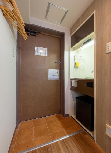 a brown door in a room with a kitchen at Sleep Inn Gotanda in Tokyo