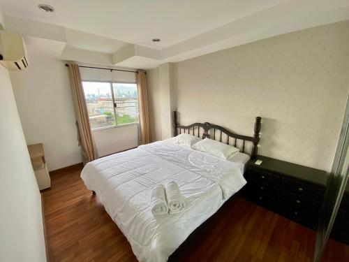 a bedroom with a bed with white sheets and slippers at ศรีย่าน เรสซิเดนซ์ Sriyan Residence in Dusit