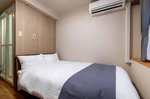 a bedroom with a white bed and a tv at Sleep Inn Gotanda in Tokyo