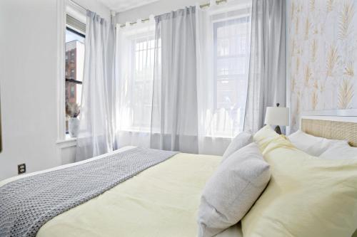 a white bedroom with a large bed and windows at Upscale 2BR Home in New York