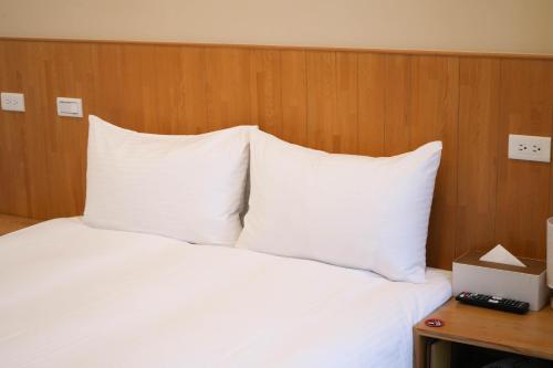 a bed with white pillows and a wooden head board at 有某行旅 yóu mǒu hostel in Tainan