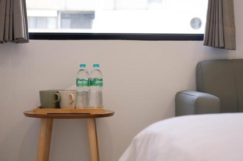 a table with two bottles of water and cups on it at 有某行旅 yóu mǒu hostel in Tainan