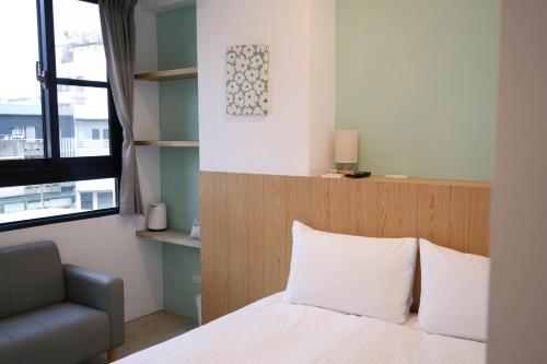 a bedroom with a bed and a chair and a window at 有某行旅 yóu mǒu hostel in Tainan