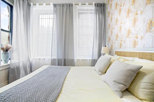 a bedroom with a bed with white sheets and a window at Upscale 2BR Home in New York