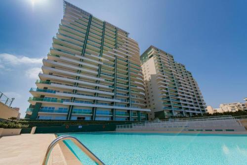 a large building with a swimming pool in front of it at 16th Floor with Pool & 180 Sea Views by QuickTrips in Sliema