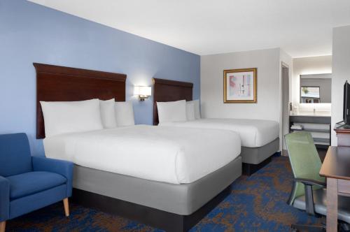 a hotel room with two beds and a chair at Hotel South Tampa & Suites in Tampa