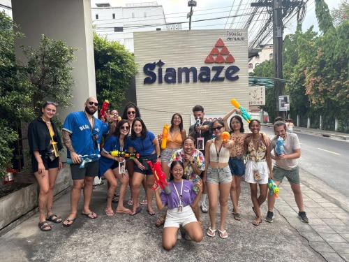 a group of people posing for a picture in front of a sign at Siamaze Hostel in Bangkok