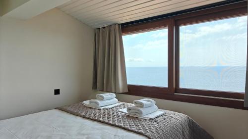a bedroom with a large window with towels on a bed at Andy's Place , Possidi By Halkidiki Villas in Possidi
