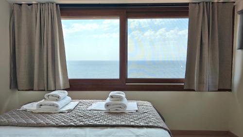 a bedroom with a window with towels on a bed at Andy's Place , Possidi By Halkidiki Villas in Possidi