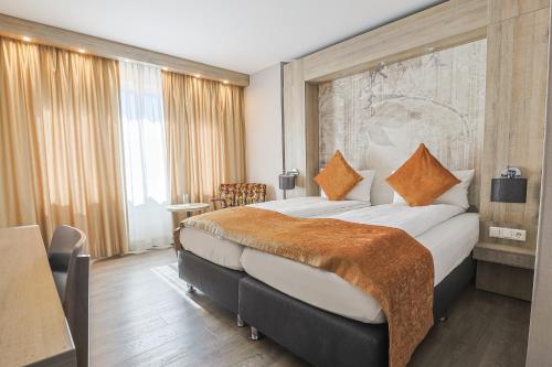 a hotel room with a large bed with orange pillows at Liebig Hotel in Ehringshausen